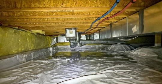 crawlspace after a water loss with standing water on the vapor barrier